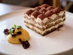 Pyszne domowe ciasta na wesele: tiramisu i mus z galaretką, udekorowane miętą.