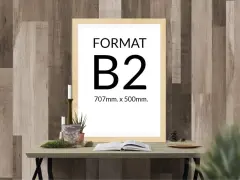 Ramka z napisem "FORMAT B2 707mm. x 500mm." na tle drewnianej ściany. Na stole obok książka i świece.