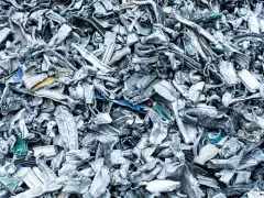Góra poskręcanego, poszarpanego złomu metalowego, gotowego do recyklingu metalu. Widać fragmenty niebieskiego i żółtego plastiku.
