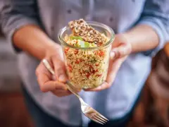 Un bocal rempli de quinoa coloré, parfait pour un régime sain. Une fourchette est prête à déguster ce plat savoureux.