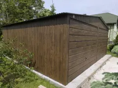 Brązowy garaż z drewnianą elewacją, z widocznymi drzwiami i dachem. Zapewnia dobrą wentylację w garażu.