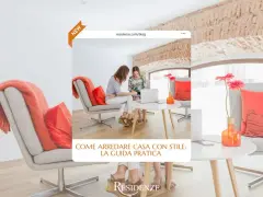 Due donne discutono idee per arredare casa in un salotto moderno con poltrone grigie e cuscini arancioni.