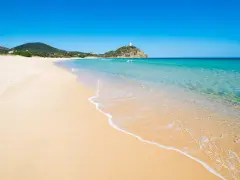 Piękne plaże Cagliari z turkusową wodą i piaszczystym brzegiem. W oddali widać wzgórze z wieżą.