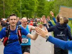Glada löpare ger high-fives under loppet. Sista veckan innan halvmarathon, peppas deltagarna av publiken.