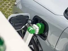 Zielony kabel ładowarki podłączony do portu ładowania samochodu elektrycznego.