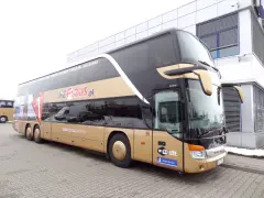 Złoty dwupiętrowy autokar Neobus.pl zaparkowany przed budynkiem.