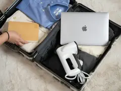 Pakowanie elektroniki w bagażu rejestrowanym: laptop, parownica do ubrań i książka.