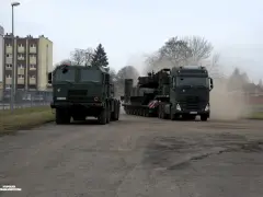 Dwa wojskowe pojazdy, w tym potężny Volvo FH16, transportują ciężki sprzęt.
