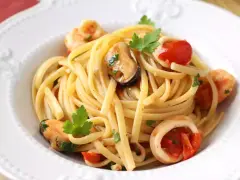 Tallarines con gambas al ajillo, mejillones y calamares, salpicados con perejil fresco y trocitos de tomate.