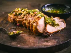 Jugoso solomillo de cerdo, cortado en rodajas y cubierto con una sabrosa salsa verde, servido en tabla de madera.