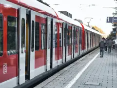 Czerwony pociąg na stacji. Ludzie czekają na peronie, zastanawiając się, jak zwrocic bilet.