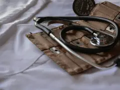 Stetoskop i mankiet ciśnieniomierza na białej tkaninie.