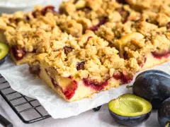 Saftiger Zwetschgenkuchen mit Streuseln, frisch gebacken und bereit zum Genießen. Daneben liegen frische Zwetschgen.