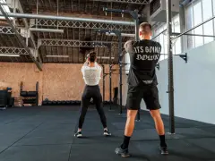 Para ćwicząca z kettlebell w siłowni CrossFit.