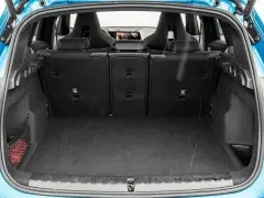 Otwarty bagażnik BMW X1, gotowy na podróż. Widoczne sportowe fotele i siatka z czerwoną gaśnicą.