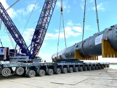 Największy transport w Polsce: potężny dźwig Sarens podnosi ogromny element instalacji na wielokołową platformę.