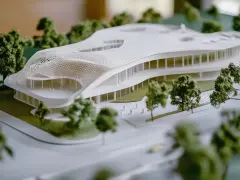 A 3D printed architectural model showcases a futuristic building with a flowing roof, demonstrating how to use 3d printing in architecture for complex designs.