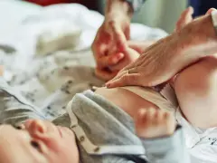 Rodzic zmienia pieluchę noworodkowi. Ile pieluch na miesiąc dla noworodka? To pytanie nurtuje wielu rodziców.