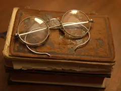 Okulary na starym oprawionym tomie, przypominające czasy, kiedy wynaleziono okulary, by czytać.
