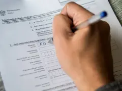 Ręka wypełnia formularz "Zgłoszenie pobytu stałego". Czy jest obowiązek meldunku? Tak, ten dokument to potwierdza.