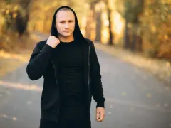 Mężczyzna w czarnej bluzie z kapturem i spodniami, idealny zestaw na fajne bluzy streetwear.