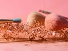 Pudry do makijażu w chmurze pyłu, pędzle do aplikacji pudru setting.
