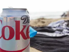 En burk Diet Coke på stranden, perfekt för den som vill undvika socker och hantera diabetes. Sukralos i drycken gör den till ett sockerfritt alternativ.