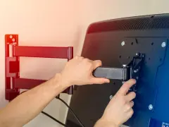 Ręce montujące uchwyt telewizyjny do ściany.