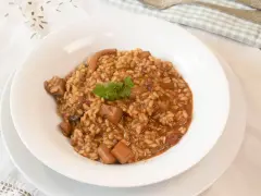 Arroz con sepia en un plato blanco, decorado con perejil.