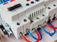 Montaż ogranicznika przepięć. Widoczne białe moduły elektryczne z czerwonymi i niebieskimi przewodami, gotowe do podłączenia.