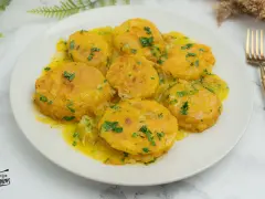 Patatas a la importancia, doradas y tiernas, bañadas en una salsa amarilla con perejil picado. Un plato que demuestra la importancia de las patatas en la cocina.
