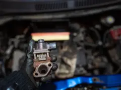 Zardzewiały zawór EGR w dłoni mechanika. Może to być przyczyna problemów z silnikiem, np. nierównej pracy.