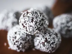 Nära bild på protein chokladbollar täckta med kokosflingor. Perfekt för ett snabbt mellanmål.