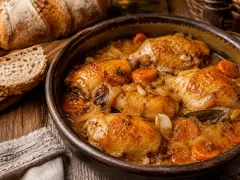 Muslos de pollo en salsa, una receta de la abuela que huele a hogar. Acompañados de pan rústico y zanahorias tiernas.