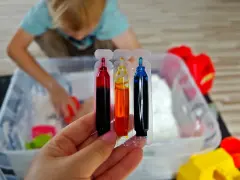 Kolorowe barwniki do piankoliny, idealne do domowego przepisu na kreatywną zabawę. Dziecko w tle miesza składniki.