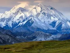 Majestatyczny, ośnieżony szczyt Denali, jednego z najwyższych szczytów kontynentów, góruje nad surowym krajobrazem.