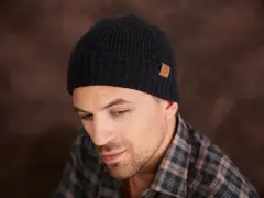 Mężczyzna w czarnej czapce z naszywką. Dowiedz się, jak zmierzyć rozmiar czapki, aby idealnie pasowała.