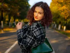 Dziewczyna w kratę, co to za styl? Ciepła flanela i zielona torebka na tle jesiennego parku.
