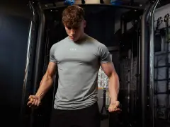 Ein muskulöser Mann trainiert im Fitnessstudio. Er fragt sich, wann er Kreatin nehmen soll, um seine Leistung zu steigern.