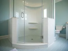 Salle de bain avec carrelage bleu pâle et une douche d'angle. Ce receveur de douche à éviter, avec ses étagères peu pratiques, est un cauchemar à nettoyer.