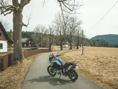 Motocykl czeka na jednodniowy wypad motocyklowy. W tle wiejskie domki i puste pola.