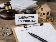Klucze do domu, mały domek, monety i dokumenty na drewnianym stole. "Darowizna bez podatku" - tekst na kartce.