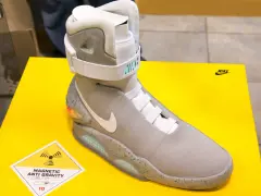 Nike Mag, najdroższe buty na świecie, z technologią "Magnetic Anti Gravity", prezentowane na żółtym tle.
