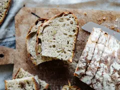 Frisches Brot mit Nüssen, perfekt **mit Dampf gebacken**, liegt auf einem Holzbrett.