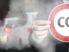 Ręka trzyma znak z napisem CO2 na tle korka ulicznego. Symbolizuje to potrzebę ograniczenia emisji, jak w przypadku certyfikatu CE dla produktów.