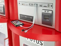 Chcesz wiedzieć, jak wywołać zdjęcia w Rossmannie? Na zdjęciu widać telefon podłączony do terminala, gotowy do druku.