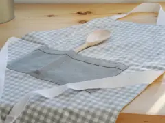 Gotowy fartuch kuchenny w kratkę, z drewnianą łyżką w kieszeni. Idealny poradnik, jak uszyć fartuch kuchenny.