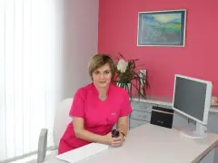 Lekarka w różowym uniformie siedzi przy biurku w gabinecie estetycznym.