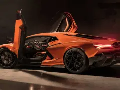 Pomarańczowy Lamborghini Revuelto z otwartymi drzwiami, ukazujący sportowe wnętrze i agresywną sylwetkę.