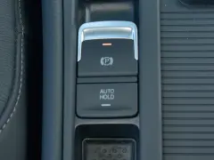 Przycisk AUTO HOLD w samochodzie. To funkcja, która automatycznie utrzymuje pojazd w miejscu po zatrzymaniu.